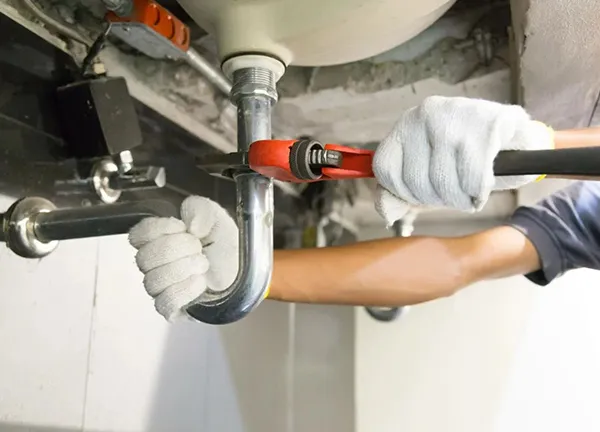 Close-up of plumber’s hands using wrench for advanced leak detection and pipe repair in Sunnyvale TX.