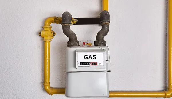 Close-up of a residential gas meter with yellow gas pipes and a gas shutoff valve.