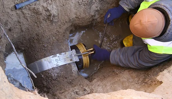Plumber using a pneumatic or power tool to excavate or repair a buried sewer line.