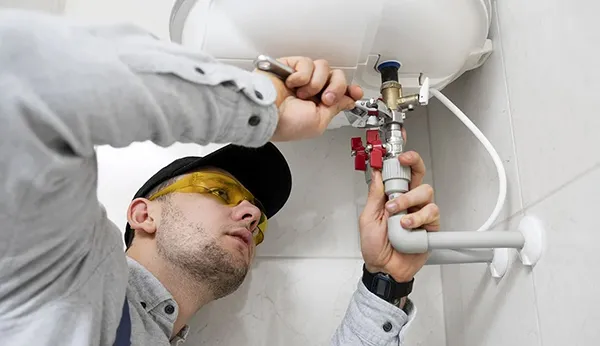 Plumber inspecting and fixing water pipes under kitchen sink for pipe repair and replacement in Heartland TX.