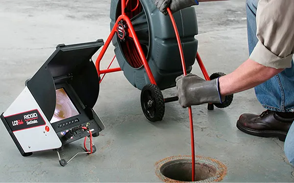 Technician operating professional drain cleaning camera equipment to inspect clogged drain pipe in Mobile City TX.