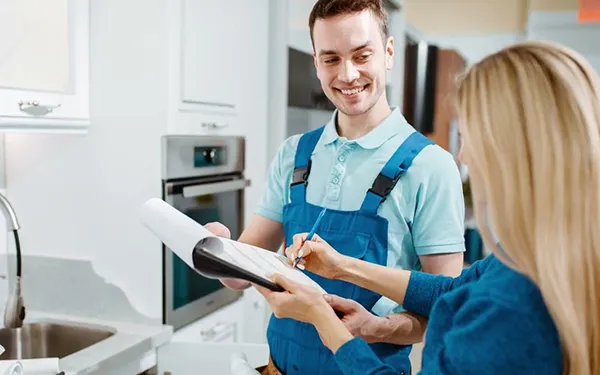 Plumber explaining plumbing repair plan to customer in kitchen for home plumbing repair services in Terrell TX.