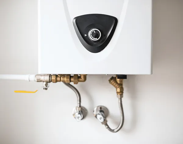 Close-up of tankless water heater control panel and plumbing connections in Travis Ranch TX.
