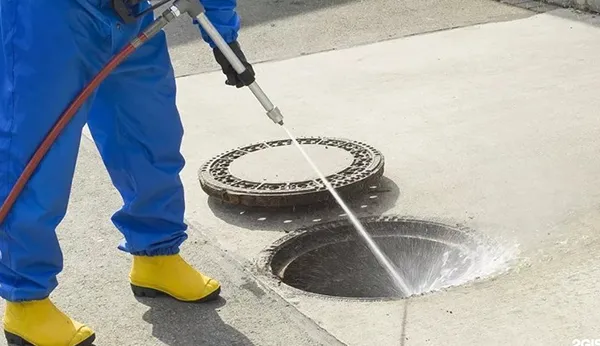 Formally dressed drain cleaning professional using high-pressure water jet to clean an outdoor drain in Hutchins TX.